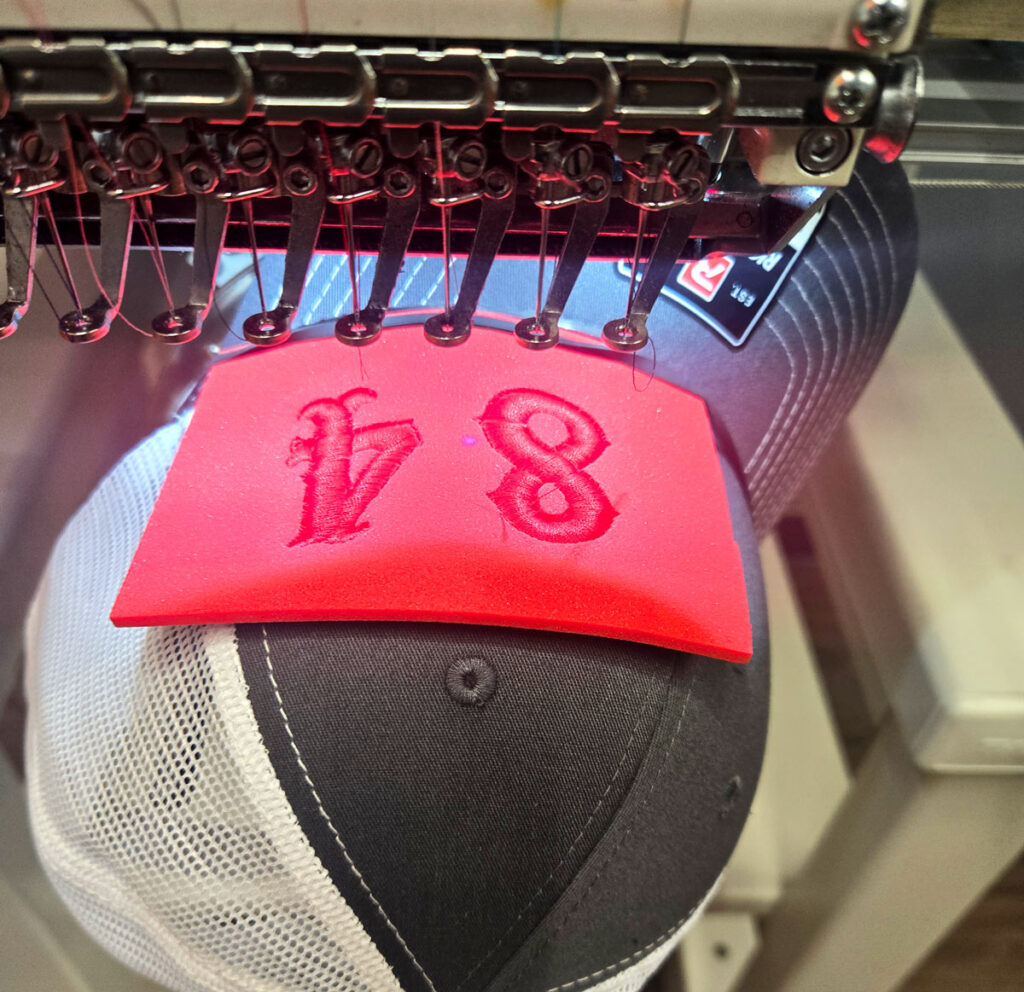 Custom 3D puff embroidery on a Station 84 cap being produced on a commercial embroidery machine by Ugly Guppy Productions in Houston, Texas.
