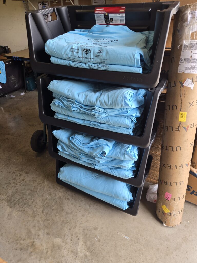Stacks of completed screen-printed shirts ready for a Houston customer order